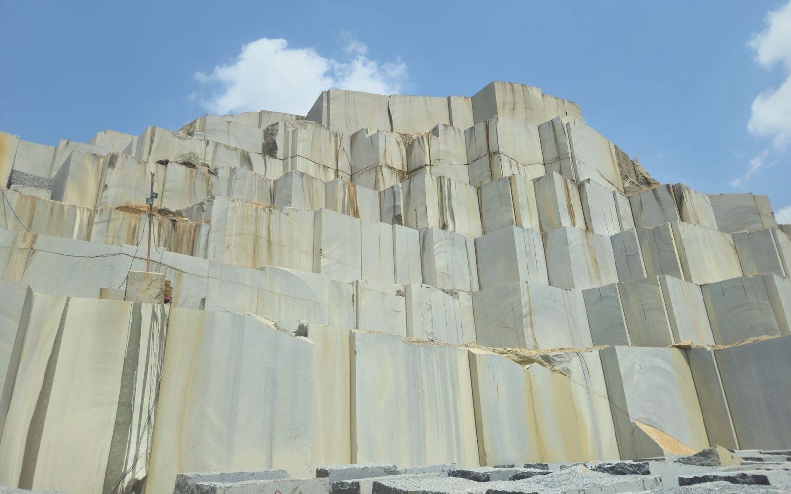 Massive cut sandstone blocks form a quarry wall beneath a blue sky