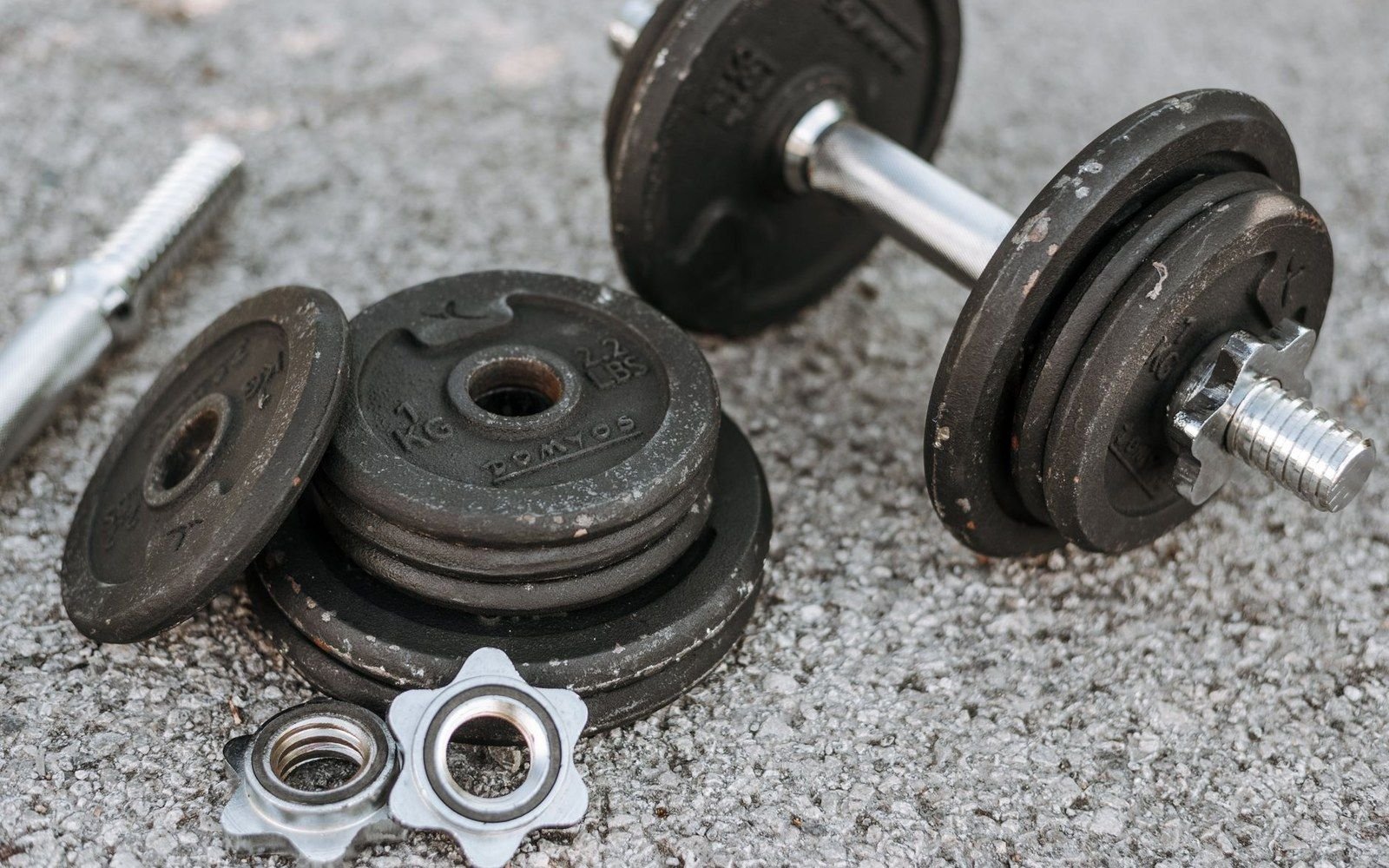 Adjustable dumbbell with weight plates and locking collars laid on a concrete surface